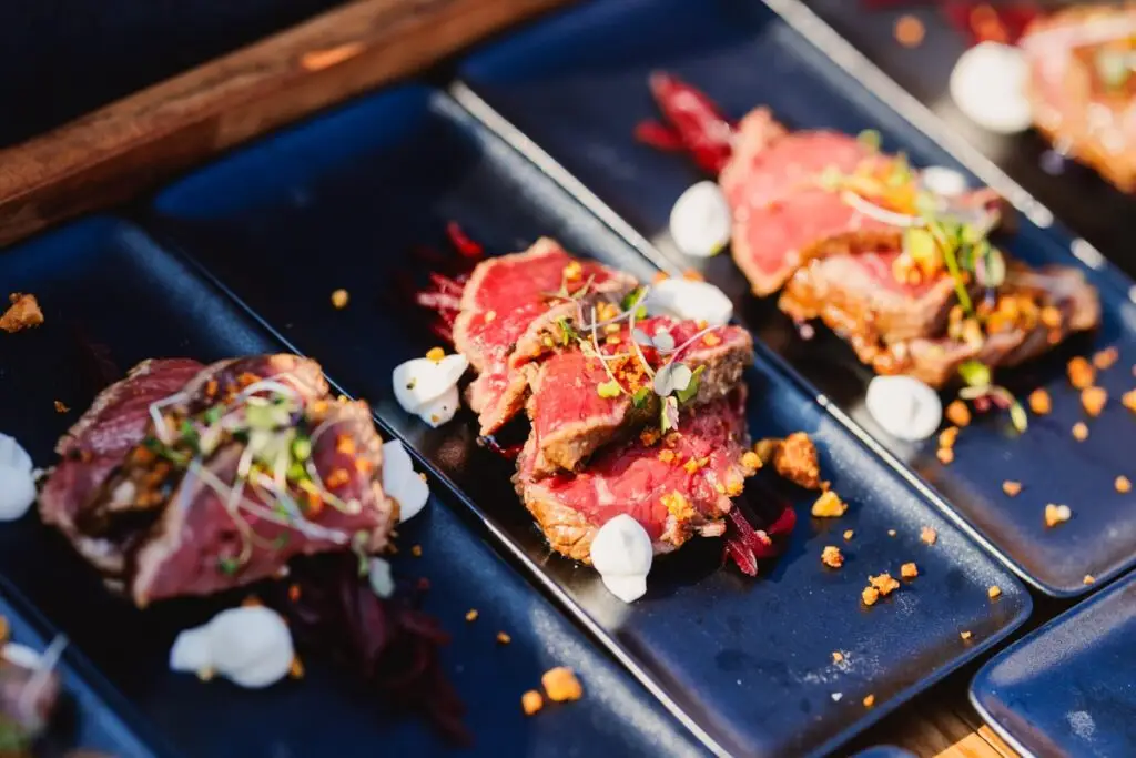 Beef tataki op zwarte borden met garnituren, walking dinner stijl