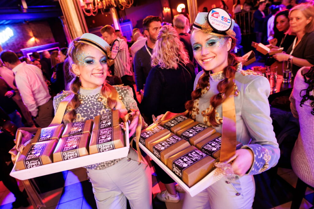 Twee hostessen delen originele hamburgers uit op een feestelijke bedrijfslocatie